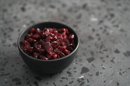 Dried cranberries in black bowl on concrete surface, shallow focusの写真素材