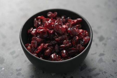 Dried cranberries in black bowl on concrete surface, shallow focusの写真素材