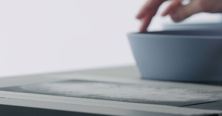 man hands sand bottom of blue ceramic bowl, wide photo