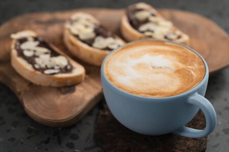 Fresh cappuccino in blue cup with toasts with chocolate spread on concrete background, shallow focusの写真素材