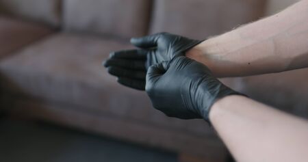 man hands takes off black nitrile protective gloves indoors, wide photoの写真素材