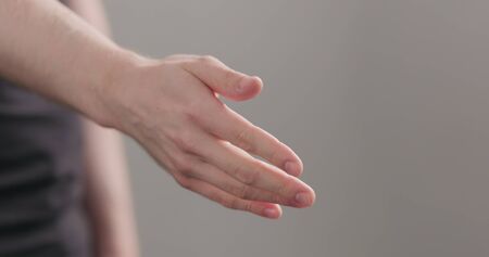 man stretches hand for a handshake or help on neutral background, wide photoの写真素材