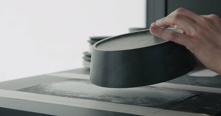 man hands check bottom of black ceramic bowl, wide photoの写真素材