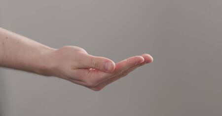 man stretches empty cupped hand on neutral background, wide photoの写真素材