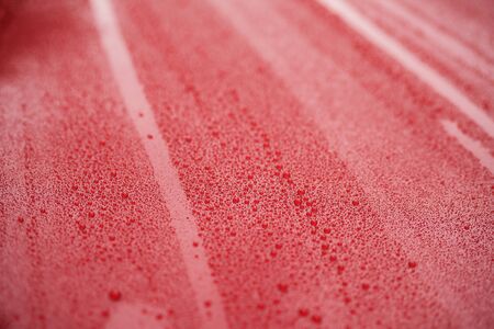 Closeup red car paint surface with hydrophobic ceramic coating, shallow focusの写真素材