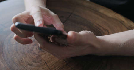 Closeup young man use smartphone while sitting at the tableの写真素材