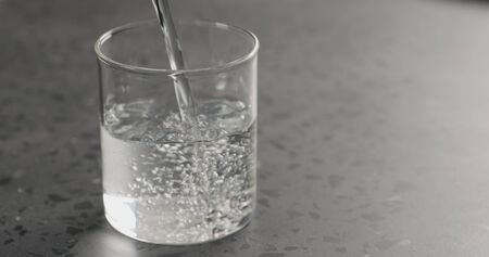 Pour clean fresh water in beaker glass on concreteの写真素材