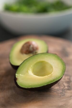 Ripe avocado sliced in halves on olive wood board closeup, shallow focus
