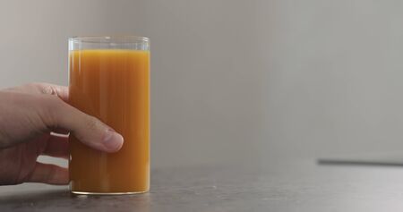 man hand take glass of fresh sea buckthorn juice from concrete surface, wide photoの写真素材