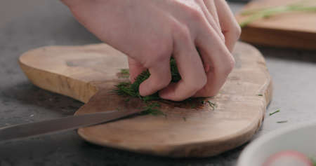 man takes chopped dill from olive board side viewの写真素材