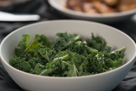 kale salad leaves in white bowl on linen napkin with other ingredients on backgroundの写真素材