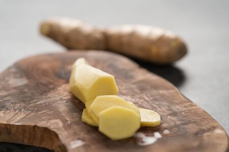 Sliced fresh ginger root on olive wood board, shallow focusの写真素材