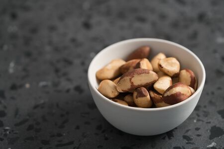 Brazil nuts in white bowl on concrete background with copy spaceの写真素材