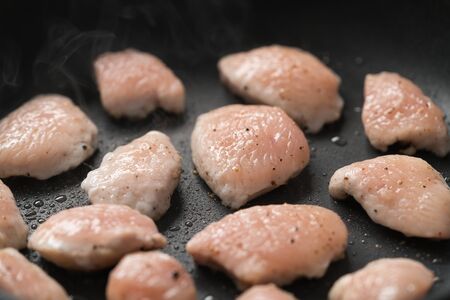 fying chicken fillet slices on nonstick panの写真素材