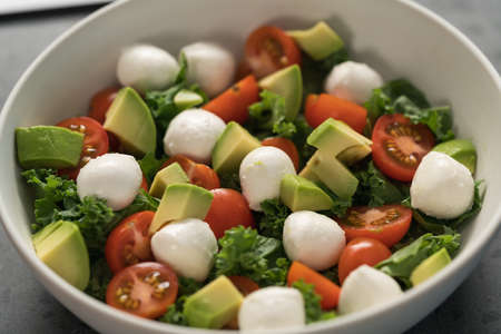 Salad with avocado, tomatoes and mozzarella closeup