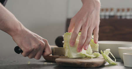 man chopping iceberg lettuce on wood board, wide photoの写真素材