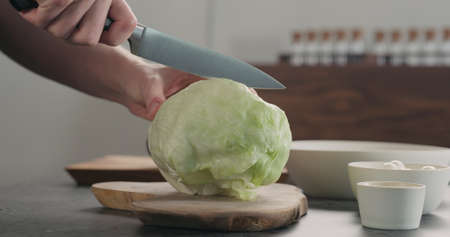 man chopping iceberg lettuce on wood board, wide photoの写真素材