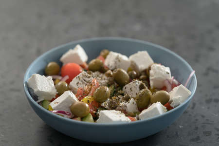 Classic greek salad in blue bowl on concrete countertp with copy space, shallow focusの写真素材
