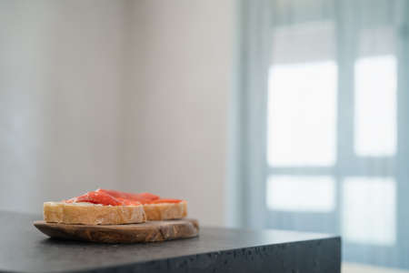 Sandwich with smoked salmon and cream cheese on olive woob board on kitchen countertop, shallow focusの写真素材