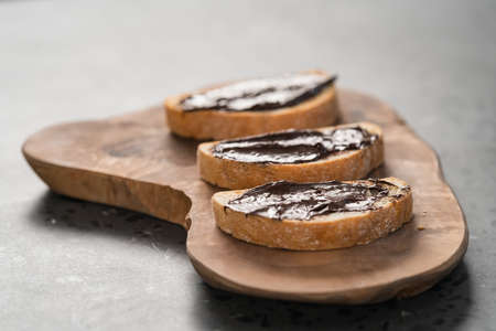 Rustic ciabatta with organic chocolate cream on olive wood board, shallow focus
