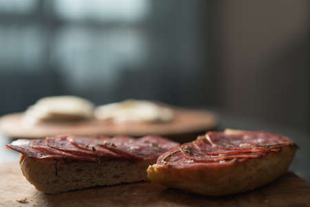 Ciabatta slices with slices of salami sausage on olive wood boardの写真素材