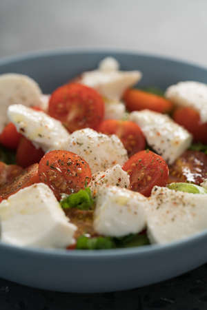 salad with mozzarella, tomatoes and lettuce in blue bowl