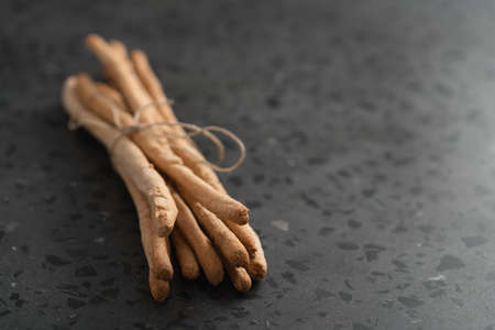 bunch of handmade wholegrain grissini tied with rope on concrete surface with copy spaceの写真素材