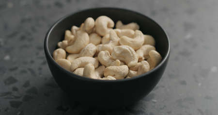 cashew nuts in black bowl on terrazzo countertopの写真素材