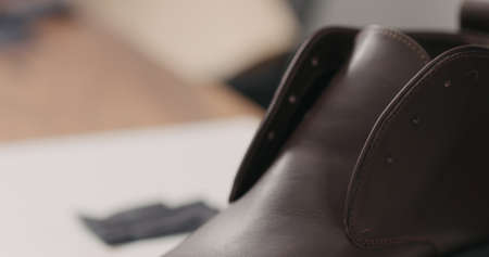 man hands in black gloves applying protective cream to brown leather chukka boots