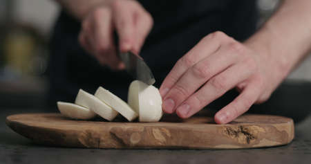 man slicing fresh mozzarella cheese on olive wood boardの写真素材