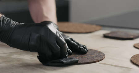 man hands applying oil finish on dark cork coasterの写真素材