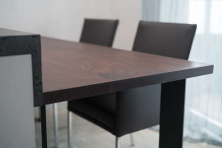 Minimalist kitchen interior with dark walnut dining table and leather armchairsの写真素材