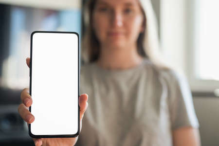 young woman show smartphone with white screen indoor with sunlight from windowの写真素材