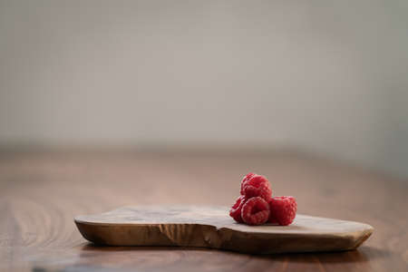 ripe raspberry on a olive wood board with copy space