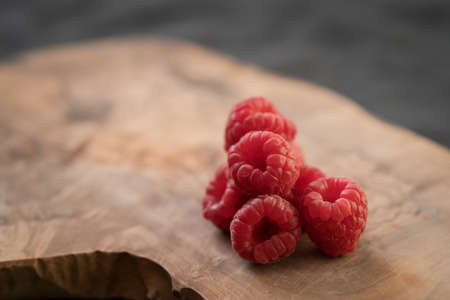 ripe raspberry on a olive wood board with copy space