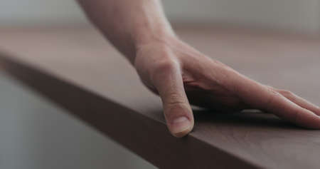 man hand checking toned walnut table surface before applying finish