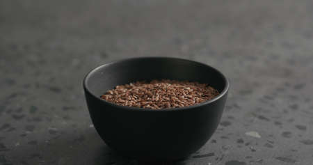 flaxseed in black bowl on terrazzo countertop with copy space