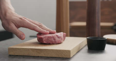 Man hand put raw ribeye steak on oak wood boardの写真素材