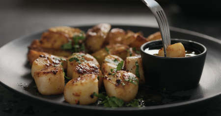 eat roasted scallops with baked potatoes on black plateの写真素材