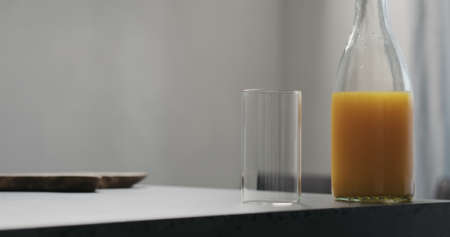 orange juice glass bottle with highball glass on concrete countertop with copy spaceの写真素材