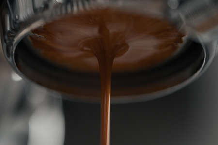 Extracting espresso with naked portafilter closeup