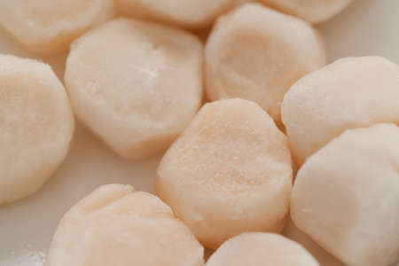 closeup of frozen scallops in white bowl on walnut table for defrostingの写真素材