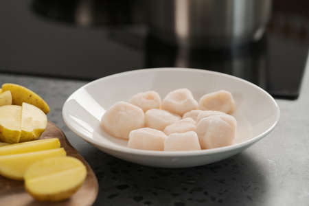 closeup of frozen scallops in white bowl on walnut table for defrostingの写真素材