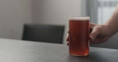 Slow motion man hand take orange soft drink in highball glass from concrete countertop with copy spaceの写真素材