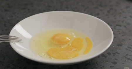 Slow motion egg fall into white bowl on concrete background