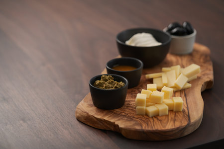 Wood board with cheese, olives and sauces on walnut table with copy spaceの写真素材