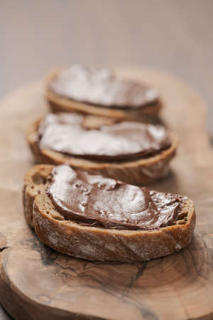 Ciabatta slices with chocolate spread on olive wood boardの写真素材