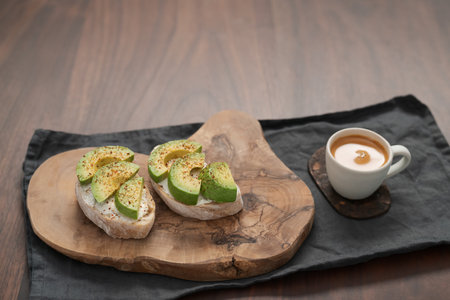 Avocado sandwiches with espresso for breakfast on walnut wood tableの写真素材