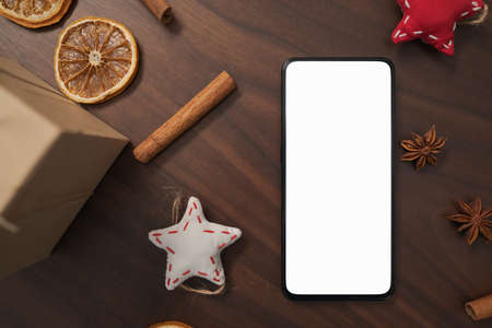 flat lay with smarthone and christmas decorations on walnut table