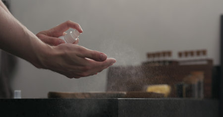man spraying sanitizer on his hands on kitchen